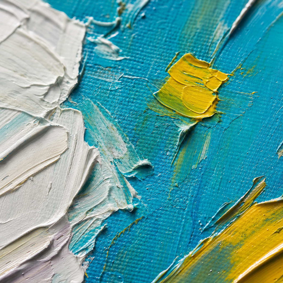 Close up of thick white and yellow palette-knife paint over turquoise canvas.