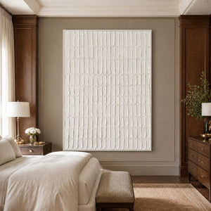 White framed cream abstract artwork beside a neutral bed and dark wooden furniture.