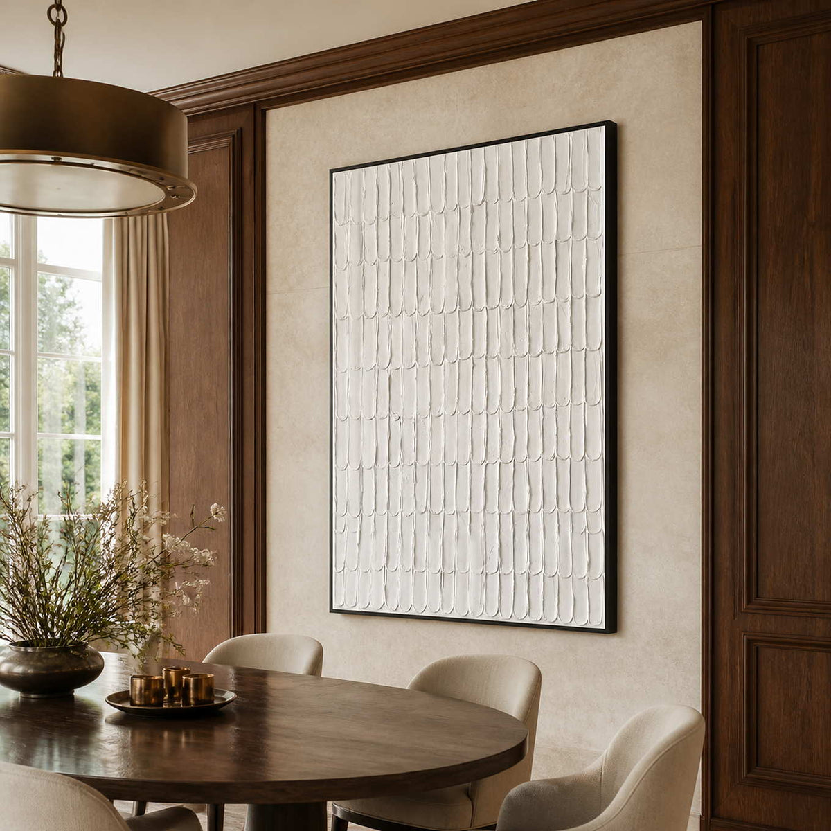 Black framed cream textured artwork beside a round wooden table in a dining room.