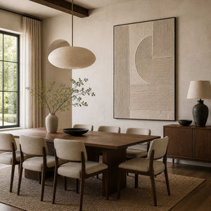 Black framed curved groove artwork beside a wood dining table and cream chairs.