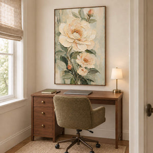 Cream flowers and soft green leaves on a muted background in a brown wood frame, displayed in a home office.