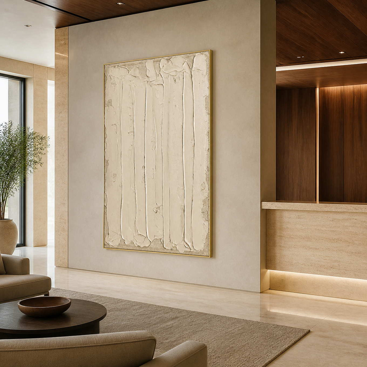 Gold framed cream abstract artwork beside a stone reception desk in a warm hotel lobby.