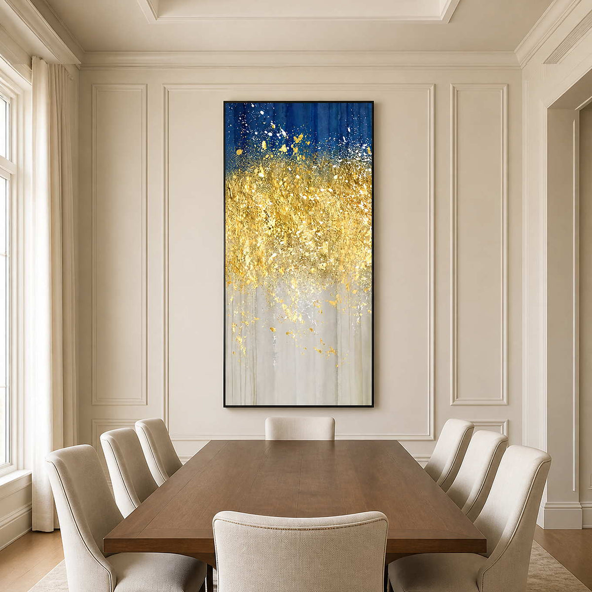 Black framed blue and gold abstract painting behind a wooden dining table with cream chairs.