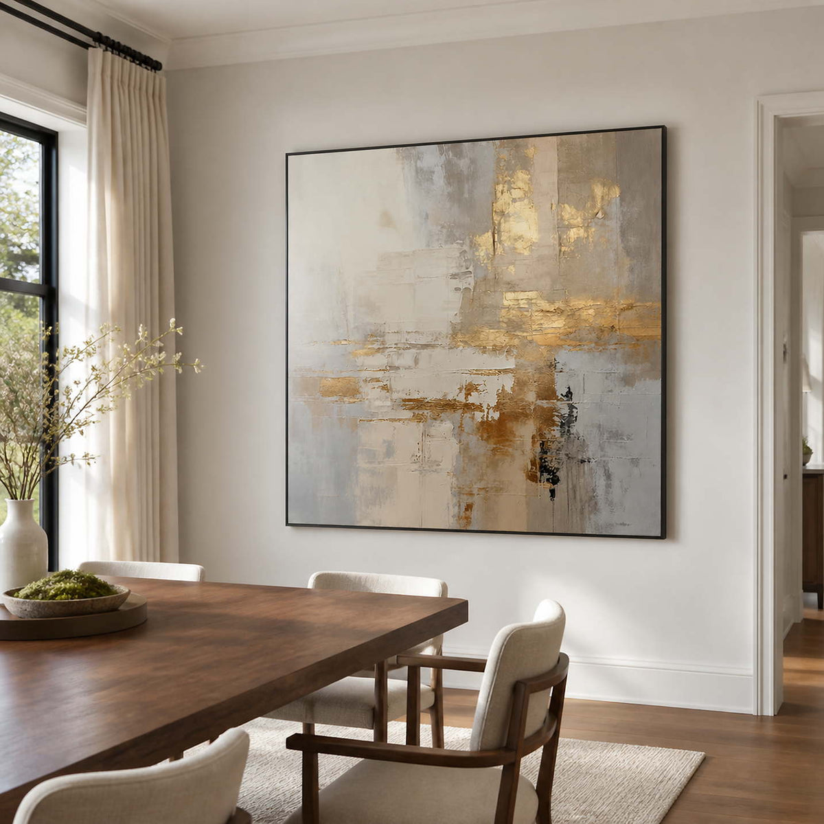 Black framed cream and gold artwork beside a wooden dining table and upholstered chairs.