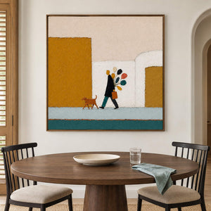A figure walking a dog past mustard buildings with a colorful bouquet in a brown wood frame, displayed above a dining table.