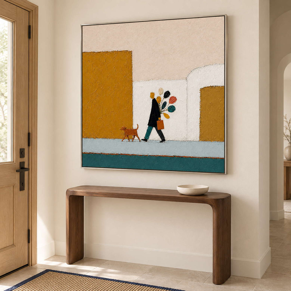 A figure walking a dog past mustard buildings with a colorful bouquet in a silver frame, displayed above an entryway console.