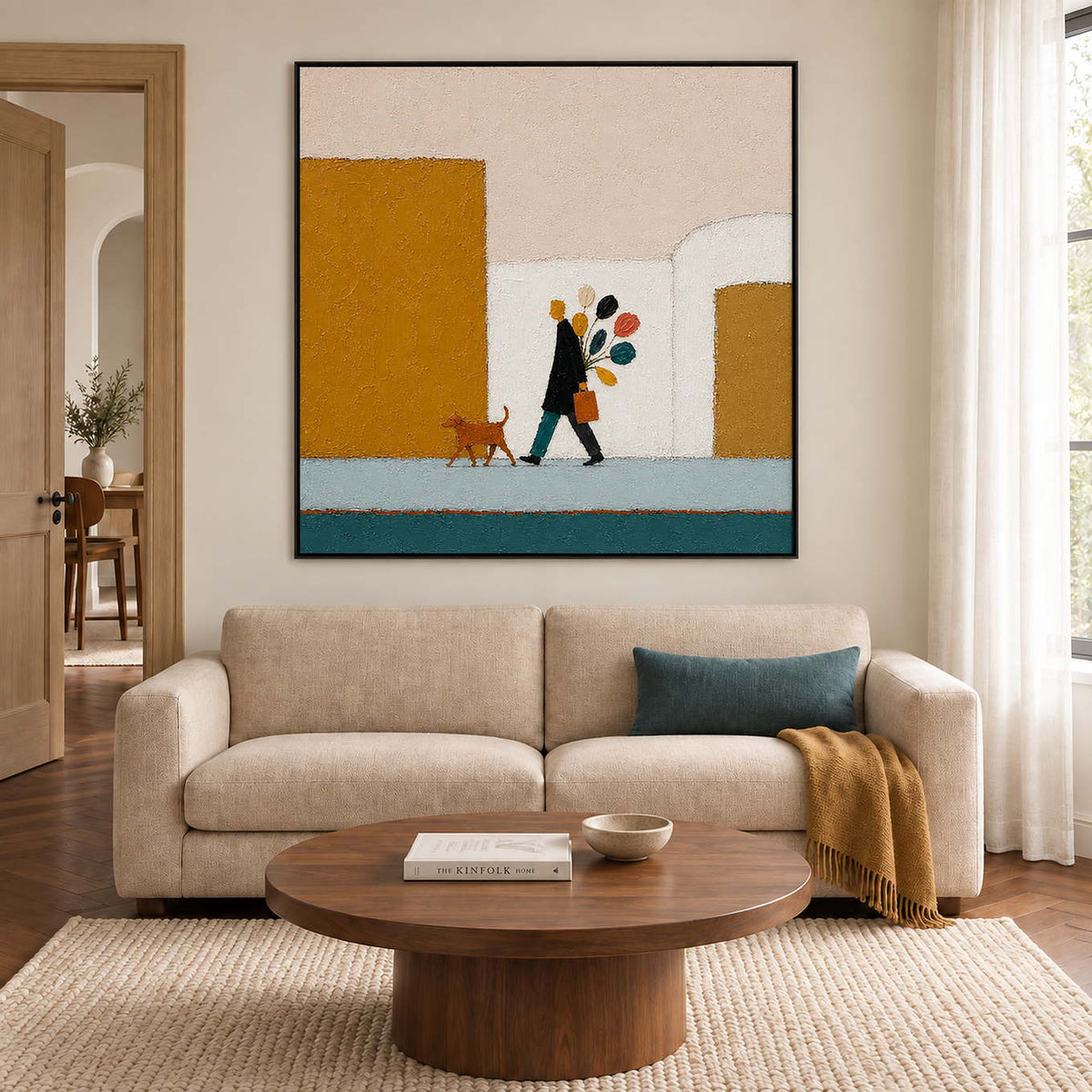 A figure walking a dog past mustard buildings with a colorful bouquet in a black frame, displayed above a sofa in a living room.