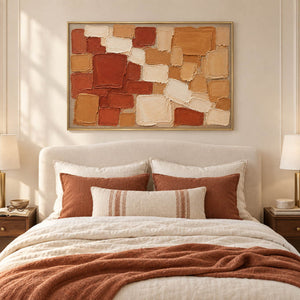 Terracotta, ochre, and cream raised block painting in a gold frame in a bedroom.