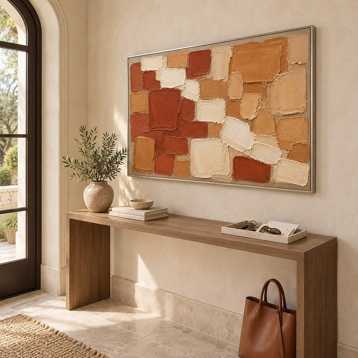 Terracotta, ochre, and cream raised block painting in a silver frame in an entryway.