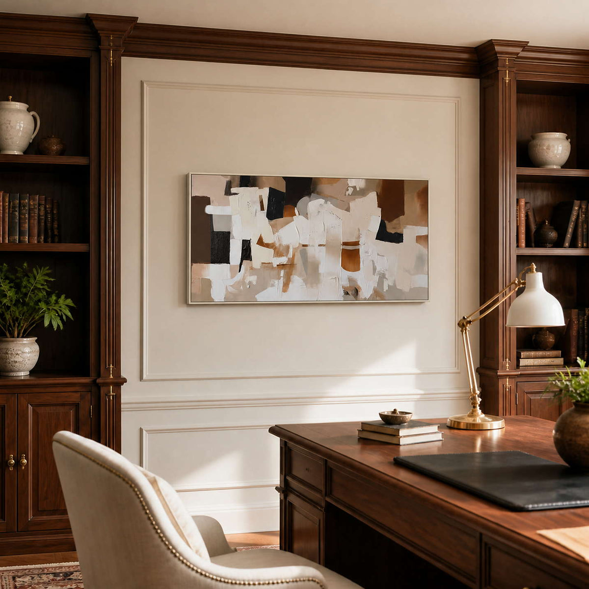 Silver framed warm abstract artwork between wooden bookshelves in a traditional study.