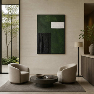 Black framed textured green artwork above two armchairs in a boutique hotel lobby.