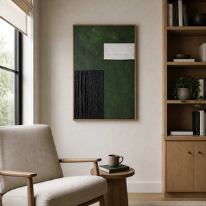 Wood framed green and black painting beside bookshelves in a home study.