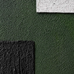 Close view of coarse green texture, raised white paint, and deep black ridges.