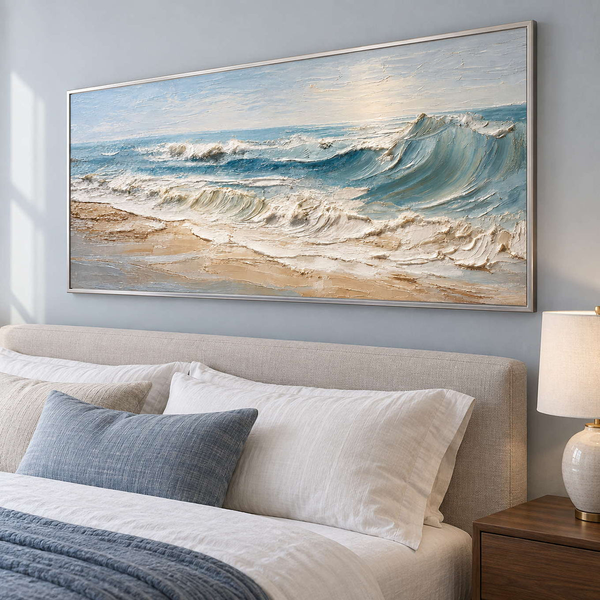 Wide foaming shore artwork above a beige headboard with blue-gray bedding.
