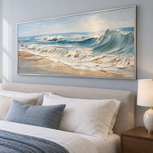 Wide foaming shore artwork above a beige headboard with blue-gray bedding.