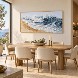 A Letter from the Waves in a gold frame above an oval wood dining table with cream chairs.