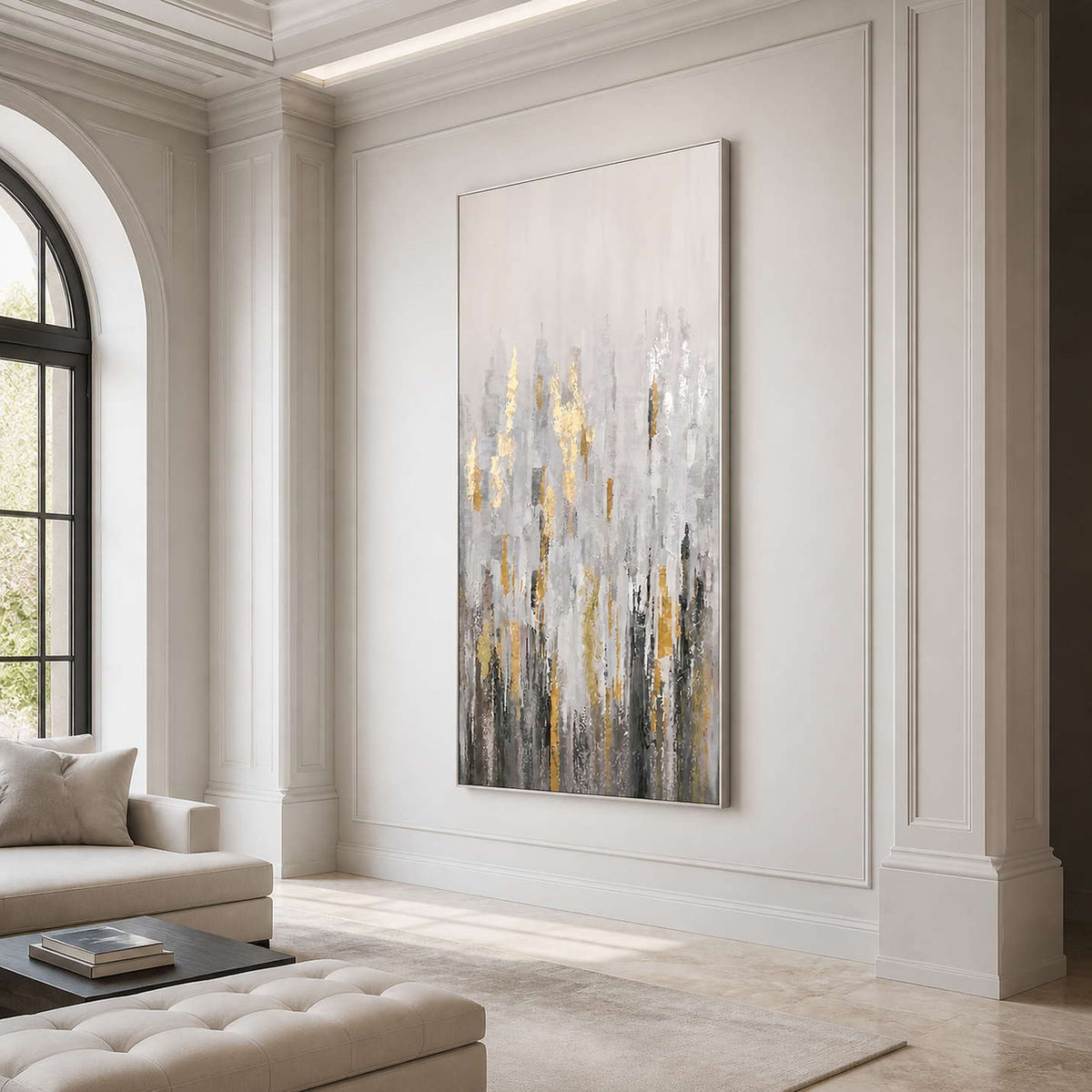 Silver framed gray and gold abstract artwork beside cream seating in a bright living room.