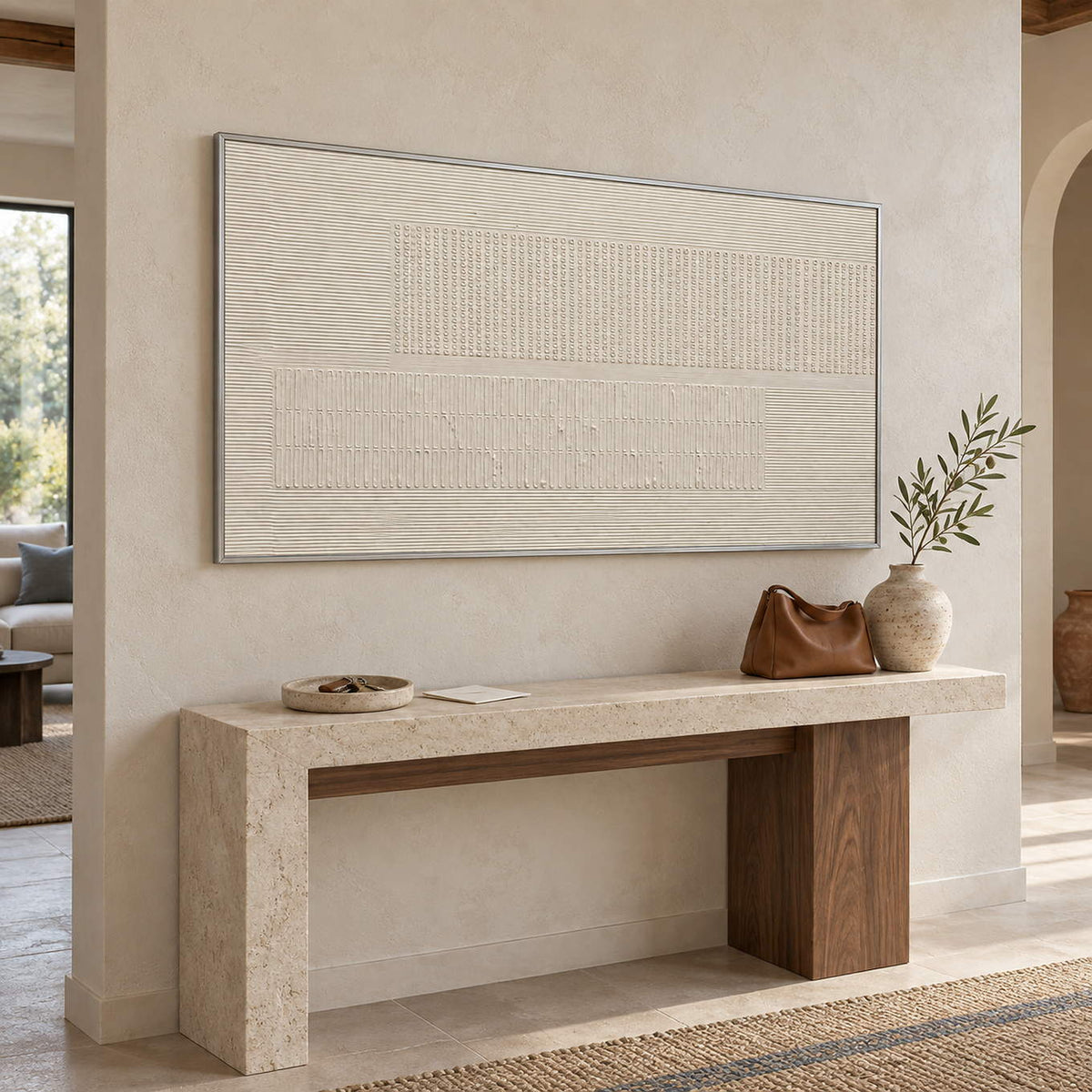 Panoramic ivory relief painting with fine grooves and geometric fields in a silver frame in an entryway.