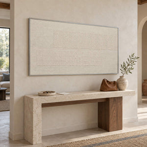 Panoramic ivory relief painting with fine grooves and geometric fields in a silver frame in an entryway.