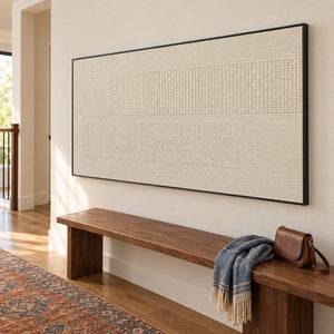 Panoramic ivory relief painting with fine grooves and geometric fields in a black frame in a hallway.