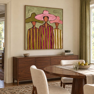 A Meeting in Style in a wood frame above a sideboard beside a round wood dining table and cream chairs.