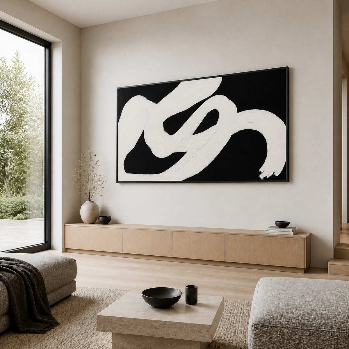 Black framed panoramic painting with white sweeping strokes above a console in a living room.