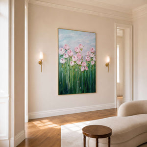 Gold framed floral artwork between brass sconces beside a cream sofa in a reception lounge.