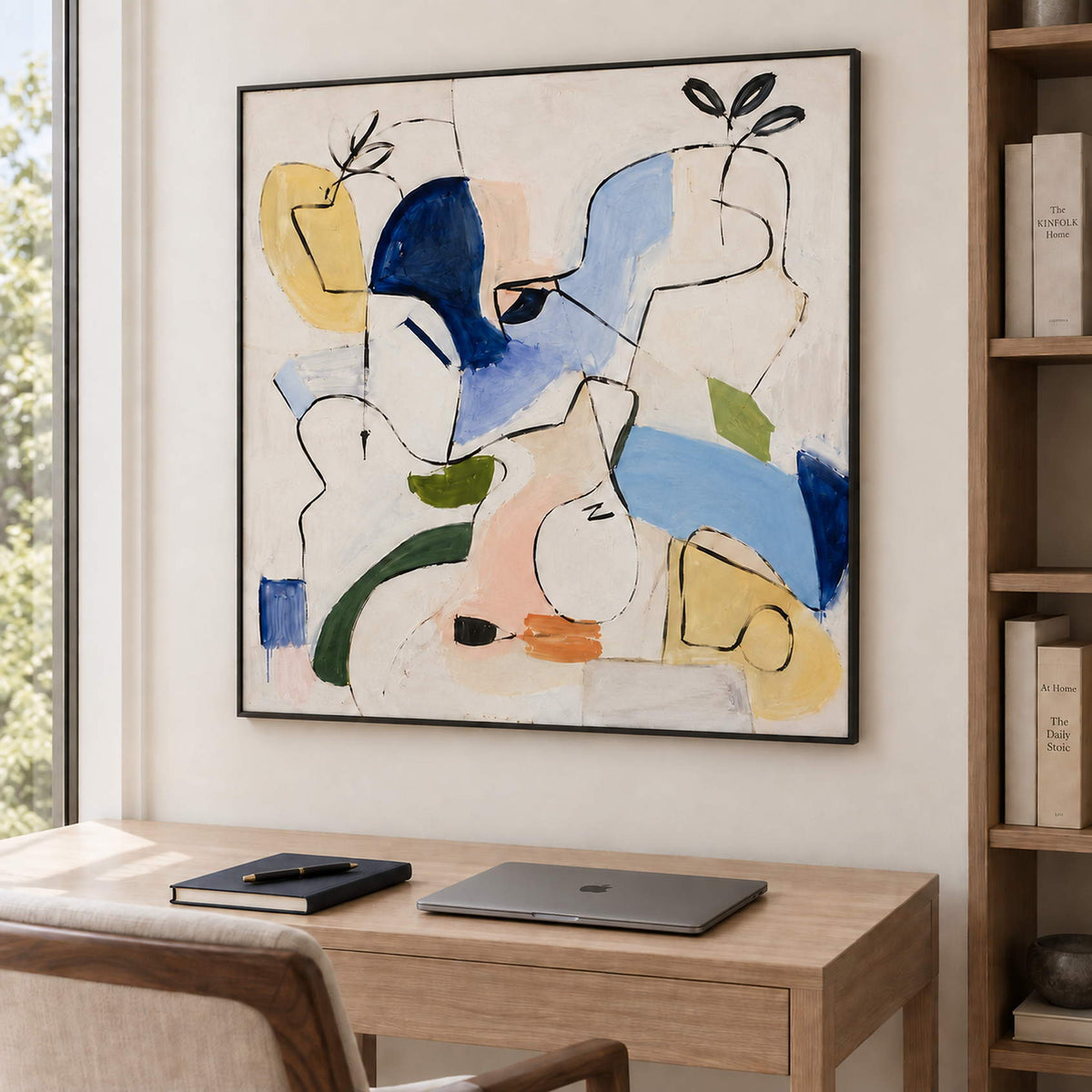 Loose black outlines and blue, yellow and green abstract shapes in a black frame, displayed in a home office.