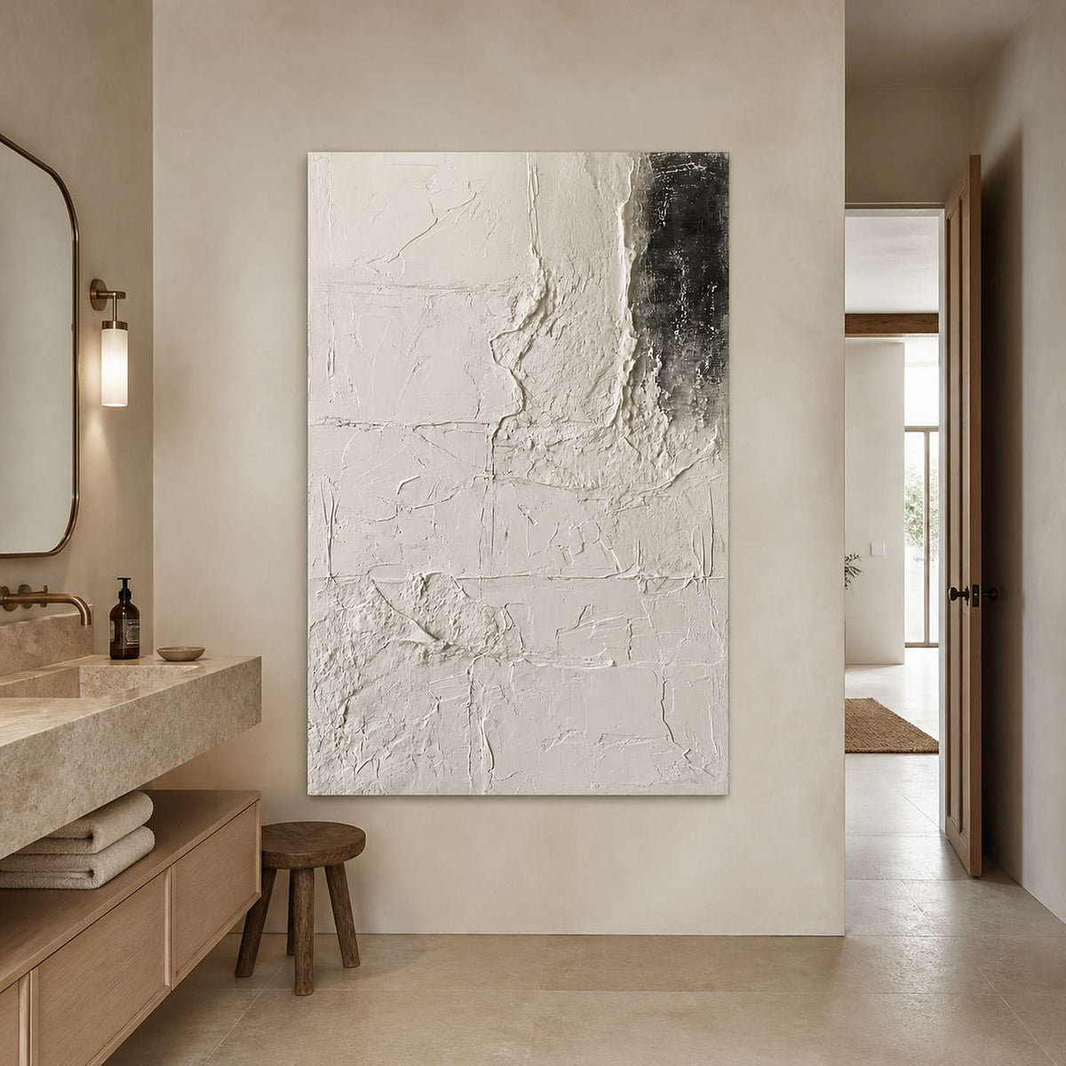 Frameless ivory abstract artwork beside a stone vanity and folded towels in a bright bathroom.
