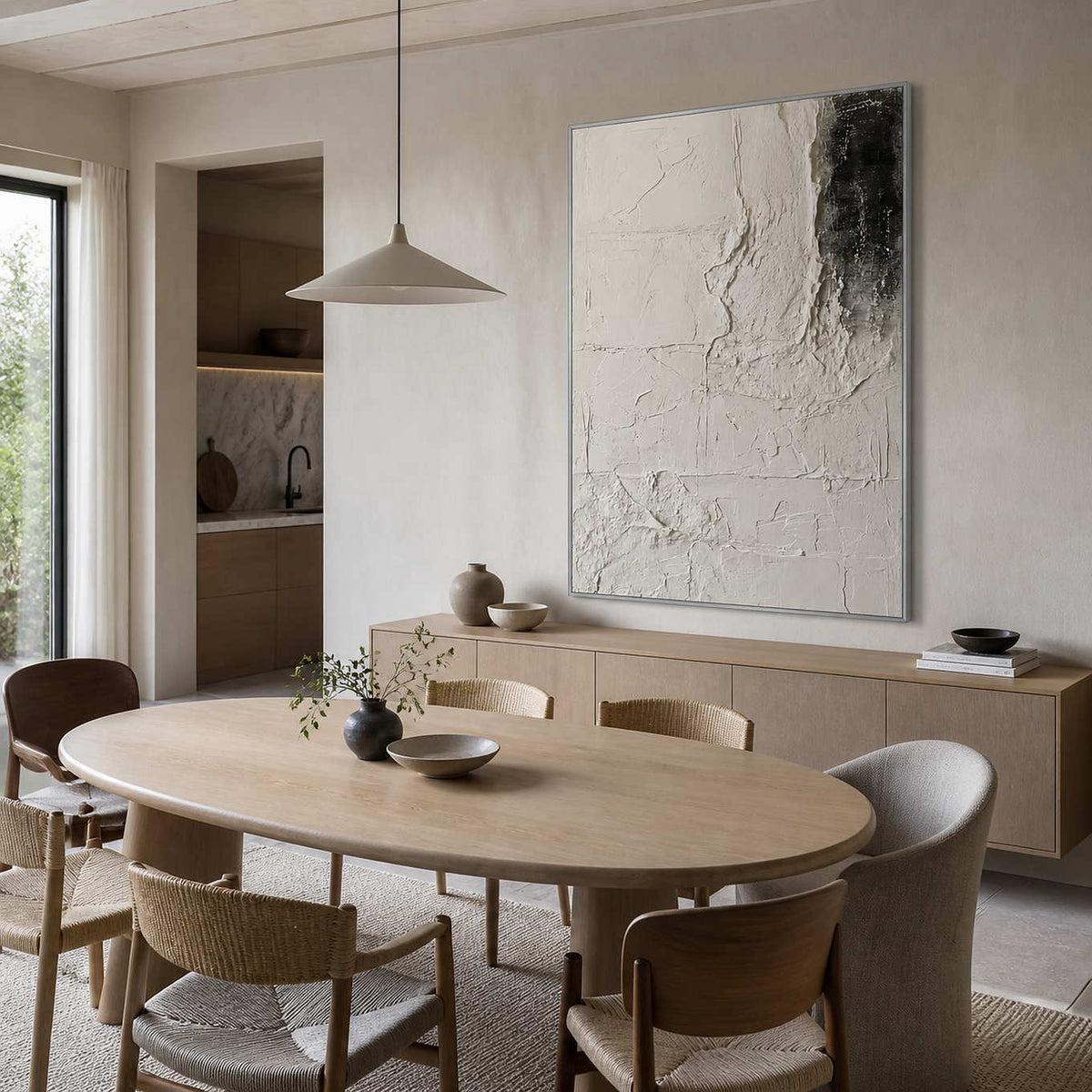 Silver framed pale abstract artwork above a sideboard beside a light oval dining table.
