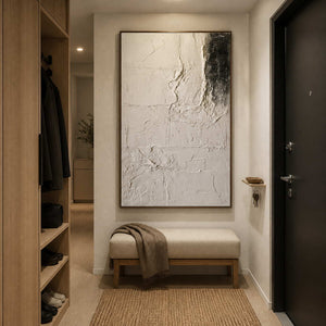 Wood framed pale abstract artwork above a cushioned entryway bench beside coat and shoe storage.