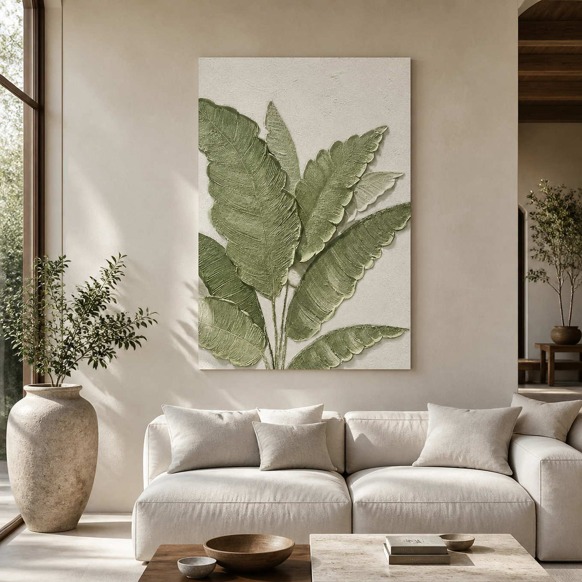 Frameless botanical wall art with green leaves above a sofa in a sunlit living room.