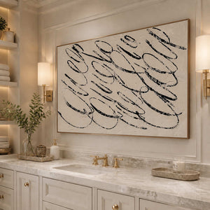 Wood framed black looping artwork above a pale marble bathroom vanity.