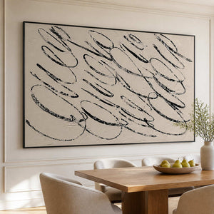 Black framed looping abstract painting above a wooden dining table with pears.