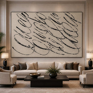 Black framed horizontal abstract loops above a cream hotel lounge sofa.