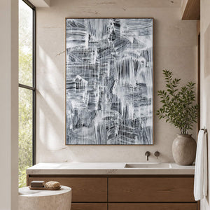 Tall gray-and-white artwork above a bathroom vanity beside a window.