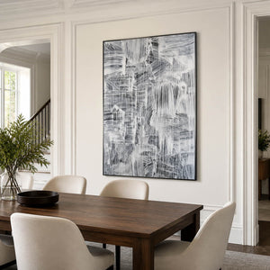 Black-and-white abstract wall art beside a wooden dining table in a paneled room.