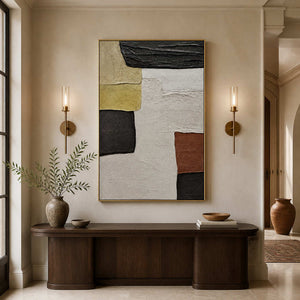 Gold-framed earthy abstract painting above a dark wood console between two wall lights in a hallway.