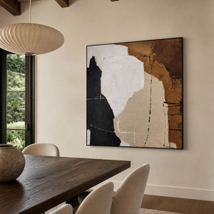 Black-framed neutral abstract artwork beside a wooden dining table and pale upholstered chairs.