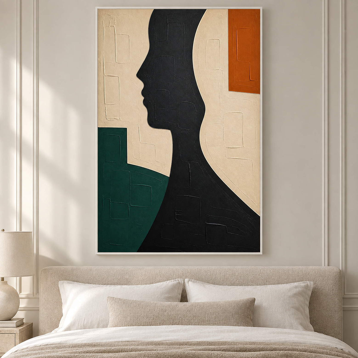 Hand-painted black profile canvas with ivory, green, and orange forms, displayed in a bedroom in a white frame.