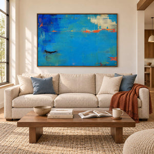 Blue and turquoise abstract painting with narrow orange streaks in a brown wood frame in a living room.