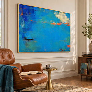 Blue and turquoise abstract painting with narrow orange streaks in a gold frame in a lounge.
