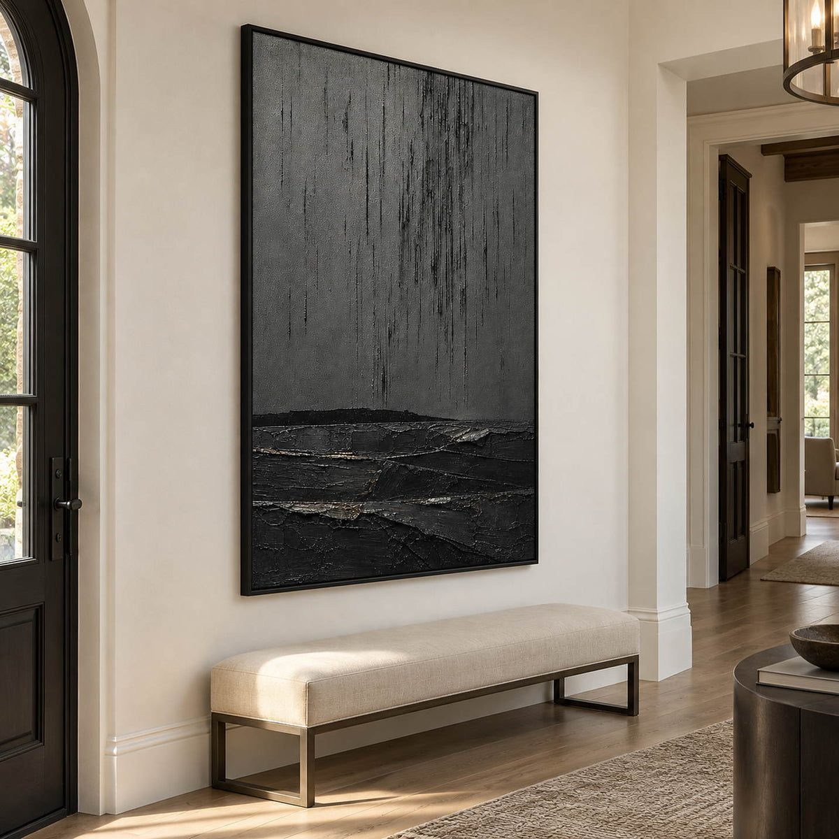 Charcoal rain marks descending over sculpted black terrain in a vertical composition, displayed in an entrance hall in a black frame.