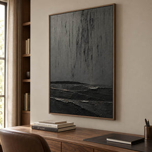 Charcoal rain marks descending over sculpted black terrain in a vertical composition, displayed in a study in a brown wood frame.
