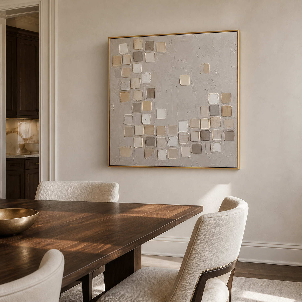 Square abstract wall art in a warm dining room with a gold frame.