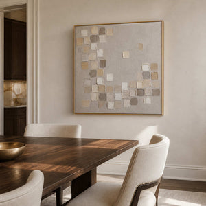 Square abstract wall art in a warm dining room with a gold frame.