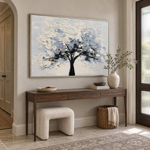 A Quiet Guardian in a silver frame above a dark wood entryway console with a cream stool and woven basket.