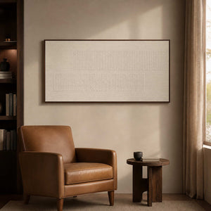 Minimalist ivory wall art beside a leather chair in a reading nook.