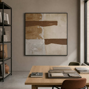 Black framed brown and cream painting displayed among samples in an architectural studio.