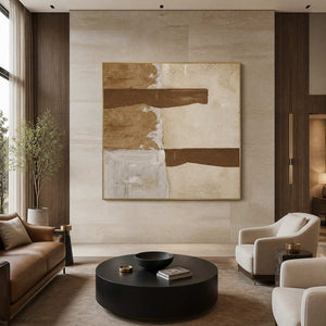 Gold framed earthy abstract painting displayed above seating in a bright hotel lobby.